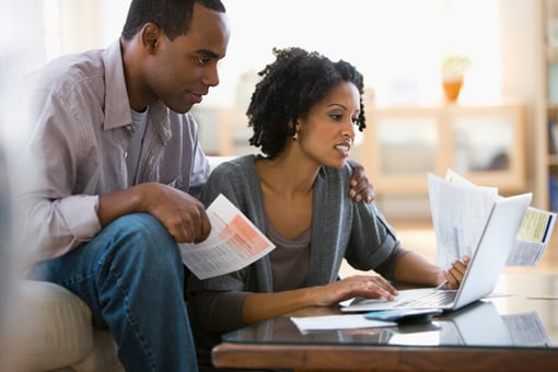 couple reviewing paper documentation and laptop