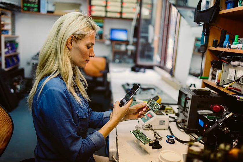 Woman looking at phone while fixing equipment